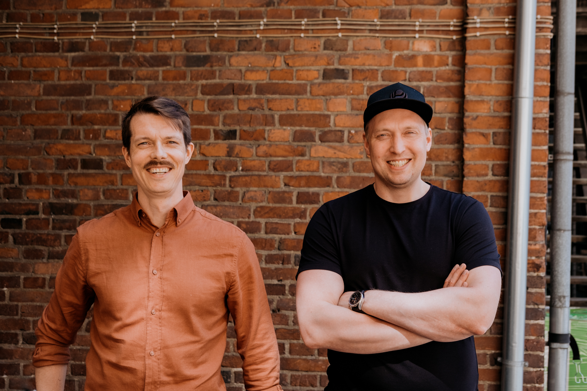 Selko Digitalin perustaja Jere Havo sekä Louhos Digitalin toimitusjohtaja Iiro Junnila hymyilevät kameralle punatiiliseinän edessä.